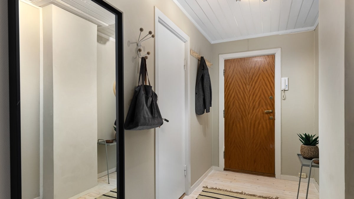 A hallway with a mirror and a coat rack